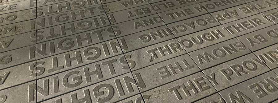 1 of 4, Close up view of new sculpture that includes embossed words on a concrete walkway