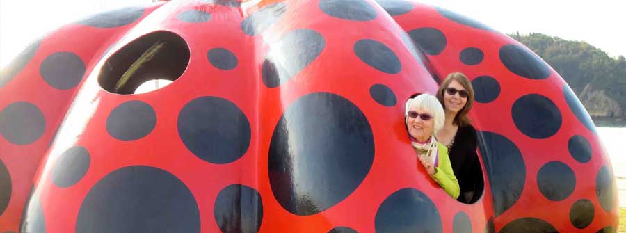 8 of 10, Two women inside a sculpture that looks like a giant red lady bug