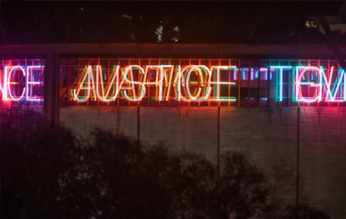 Image of Bruce Nauman's artwork titled "Vices and Virtues," large neon lights of the seven vices and virtues transposed over each other, this one depicting the word Justice.