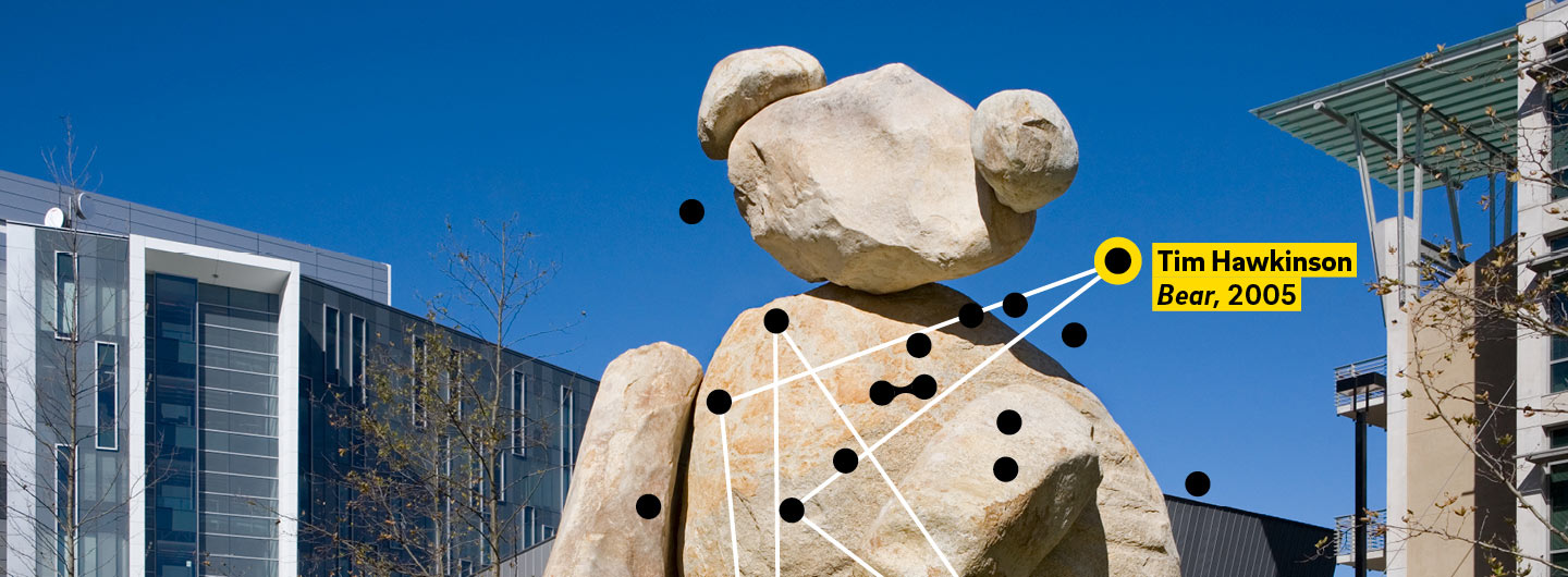 The Bear statue by Tim Hawkinson, a stone bear, in a courtyard, with graphic logo on top.